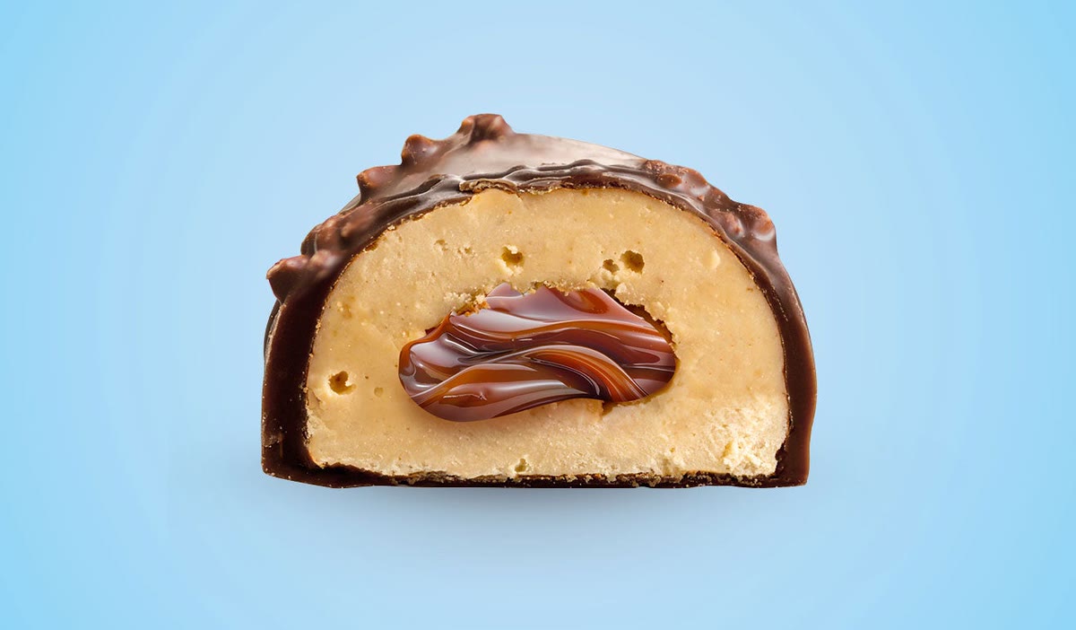 SNCK Caramel Pop protein bar cut in half: chocolate shell, soft protein dough and caramel core